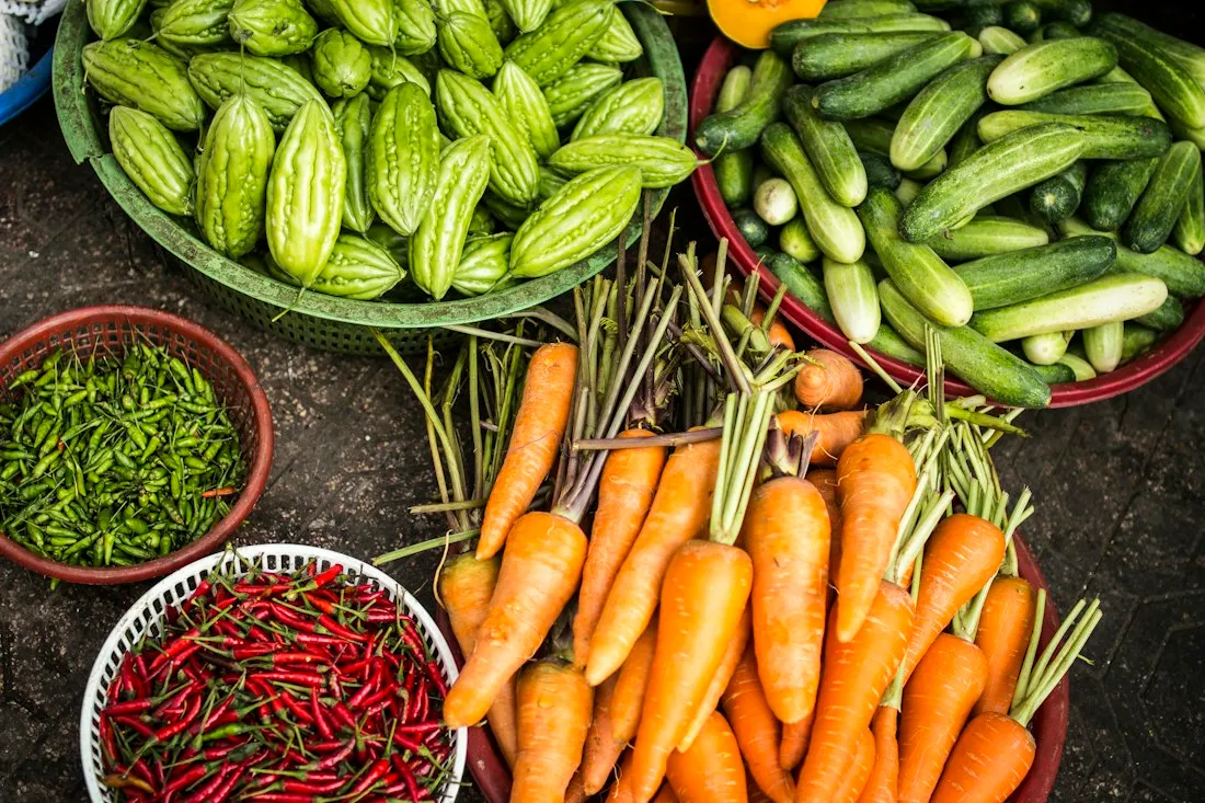 Baskets of carrots, cucumbers, bitter melons and chillies at a produce market